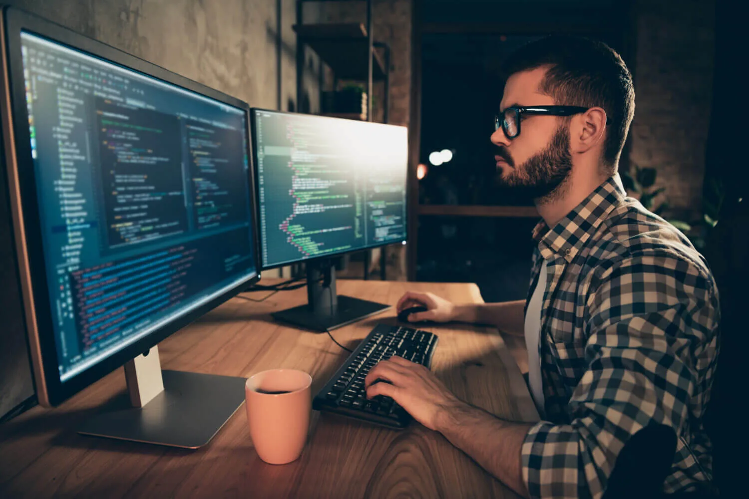 man looking at two computer screens